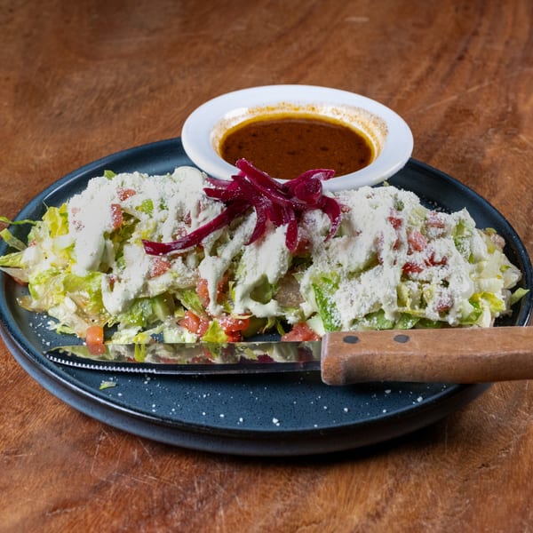 Sonora Mexican Kitchen's salad with lettuce, tomatoes, cheese, red onions, and a side of dressing.