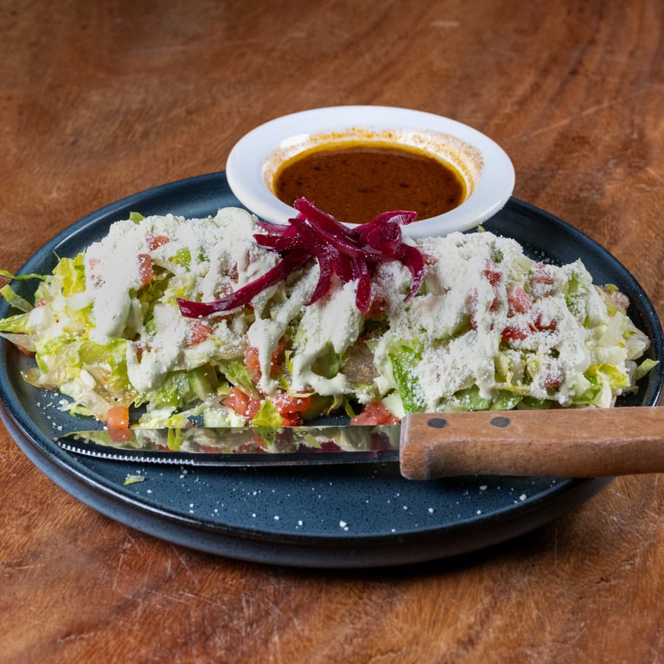Sonora Mexican Kitchen's salad with lettuce, tomatoes, cheese, red onions, and a side of dressing.