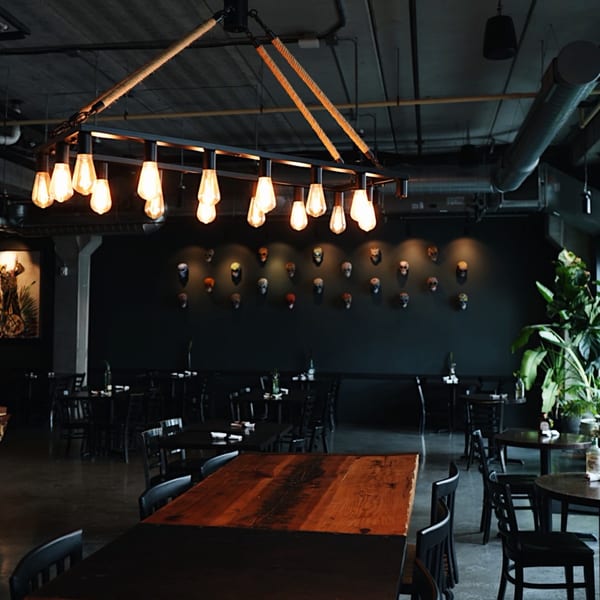 Sonora Mexican Kitchen's dimly lit dining room with dark tables, chairs, and skull decor on the wall.