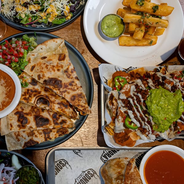 Overhead view of Sonora Mexican Kitchen and Bar's quesadillas, nachos, yucca fries, and salad.