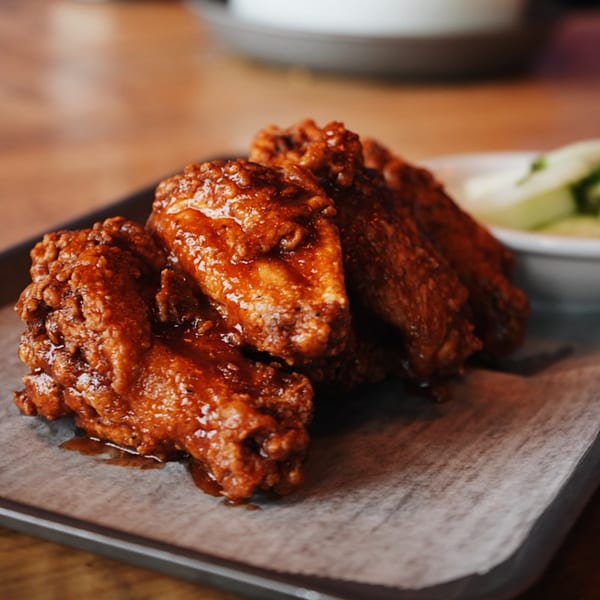 Four Sonora Mexican Kitchen and Bar chicken wings coated in a rich, glossy sauce on a tray.